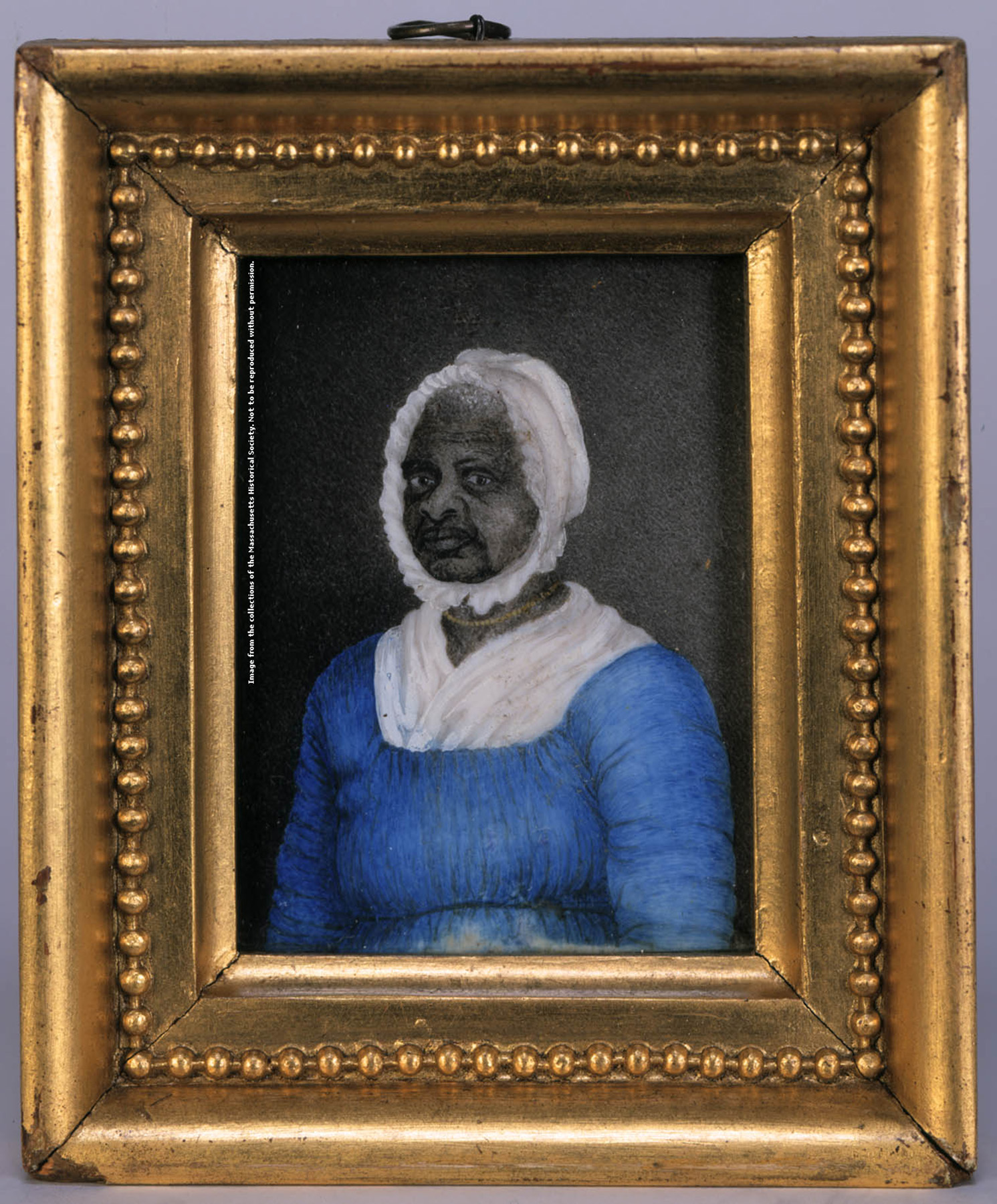 A framed portrait of a Black woman wearing a blue dress with drawstrings at the neck and waist, a white fichu tucked into her dress at the neck, a white cap, and a gold beaded necklace.