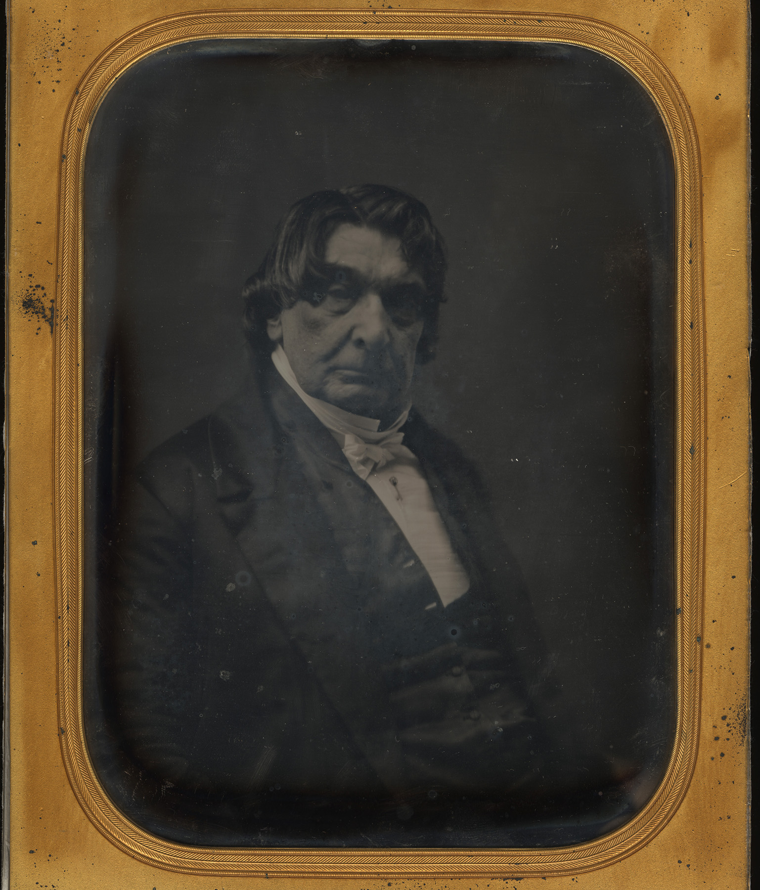 a somewhat blurry black-and-white image of a white man wearing a jacket and bowtie in a frame.