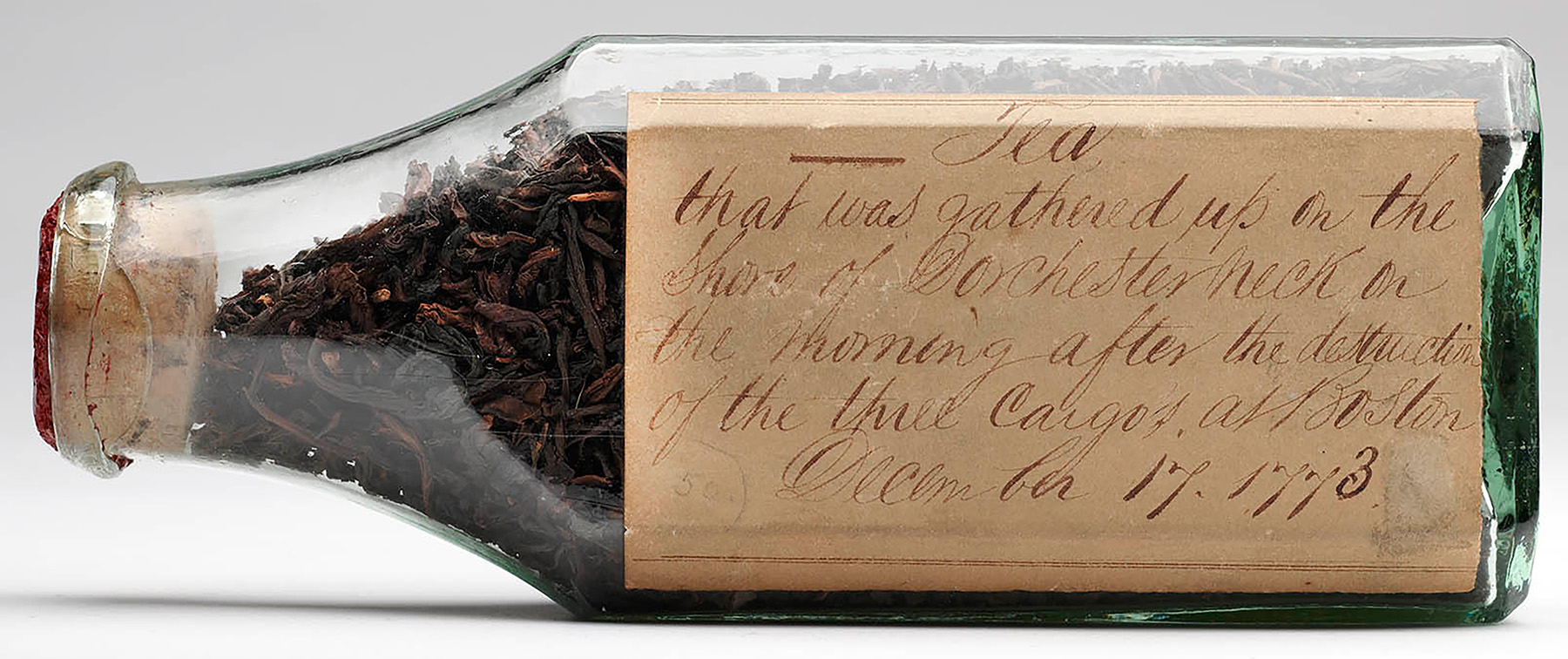 Glass bottle full of dry tea leaves positioned on its side so the handwritten label is visible